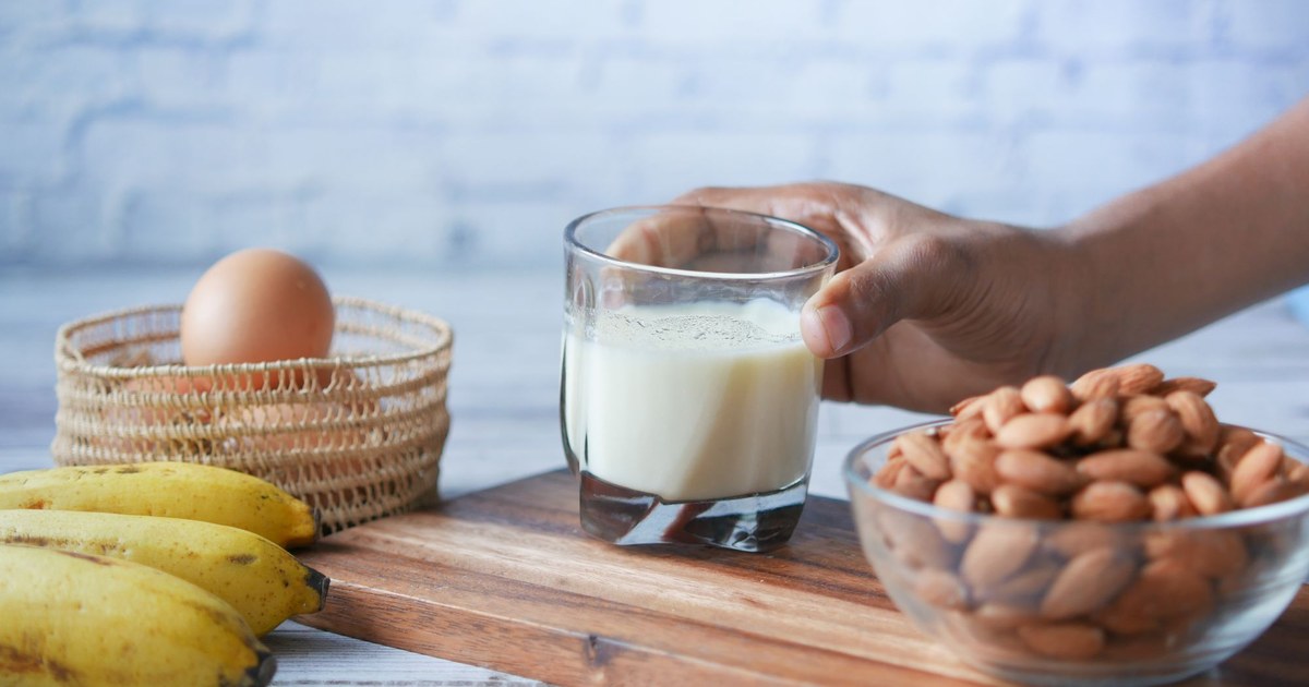 Calcium-rich foods including milk, almonds, and eggs on a wooden board