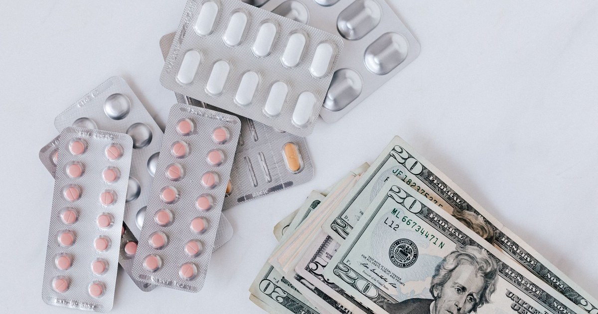 Blister packs of pills beside a stack of US banknotes