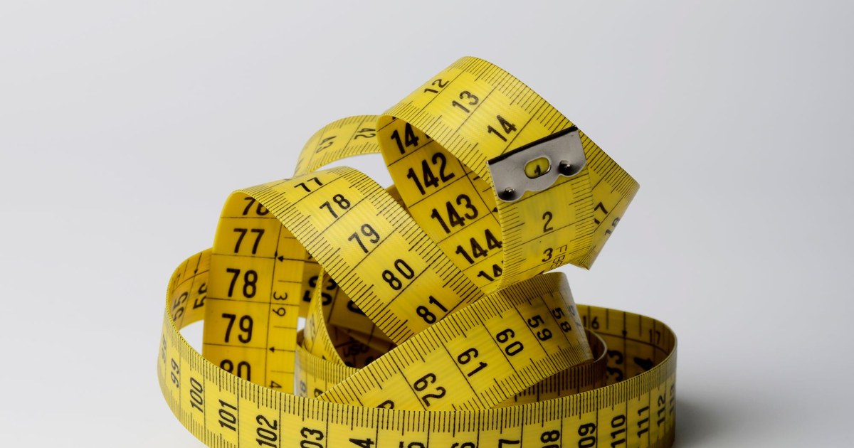 A coiled yellow measuring tape on a white background