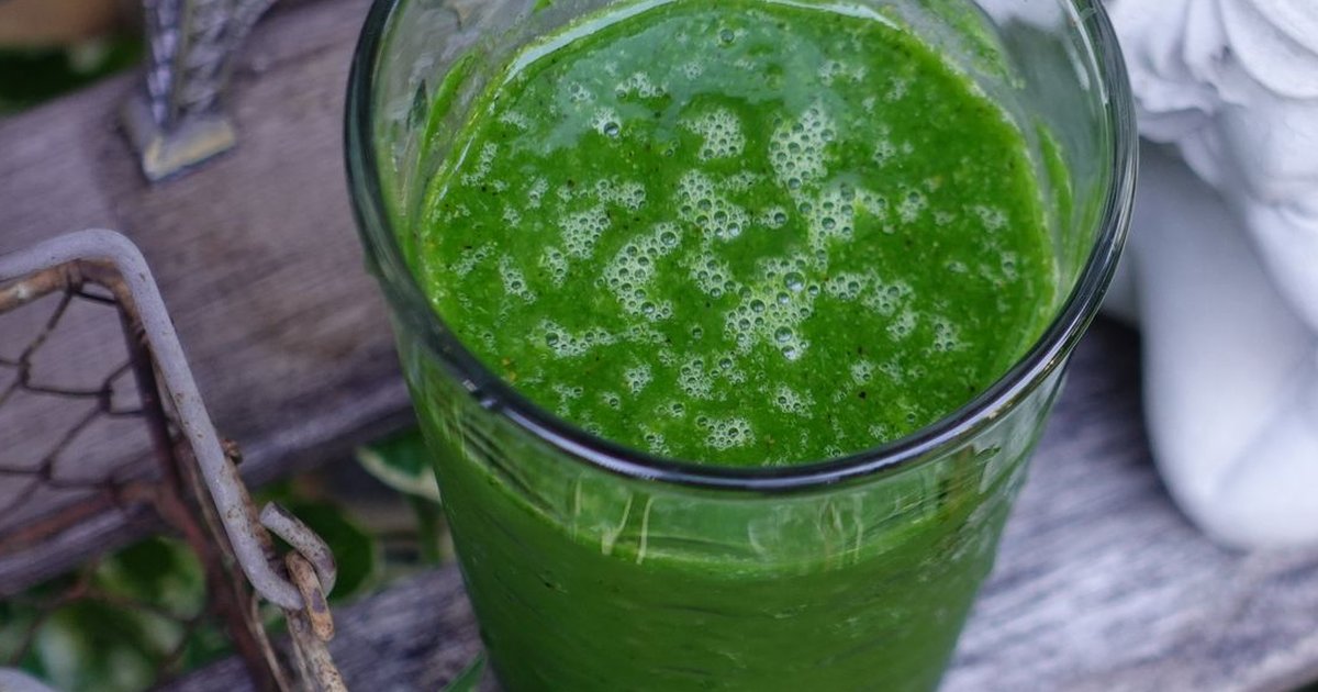 A vibrant green smoothie in a glass on a rustic table