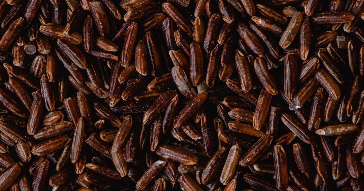 Close-up of uncooked reddish-brown rice grains filling the frame