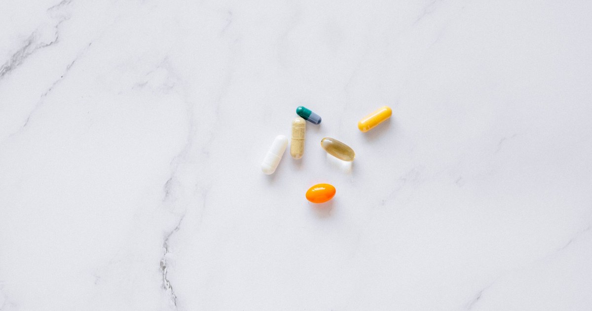 A close-up of assorted supplement capsules and tablets on a white surface