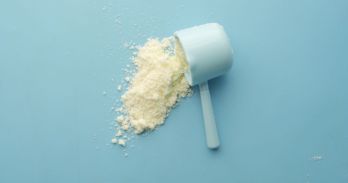 A scoop of amino acid powder spilling onto a light blue surface