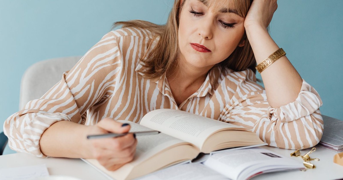 A tired woman resting her head in her hand at a desk