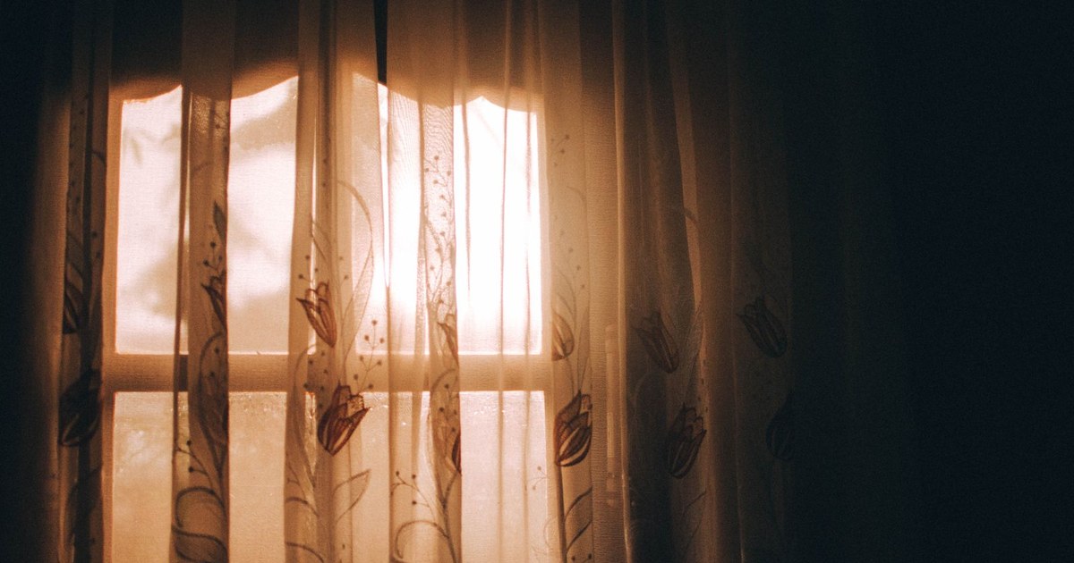 Warm morning sunlight glowing through sheer window curtains